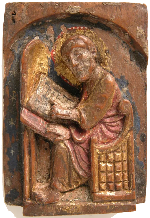 A small carved and painted wooden relief of a saint seated at a writing desk with an open book, gilded and set in an arch.